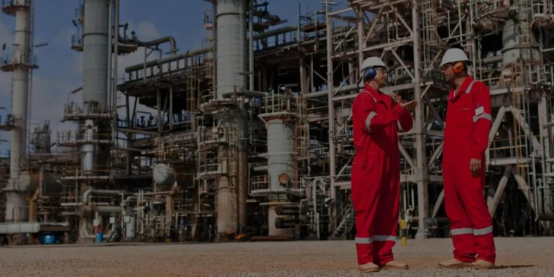 two employees talking in front of a refinery